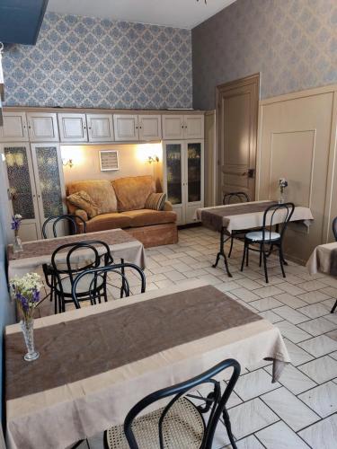 un soggiorno con tavoli, sedie e un divano di L'Entrée Chambres d'Hôtes Bar & Restaurant a Castillonnès