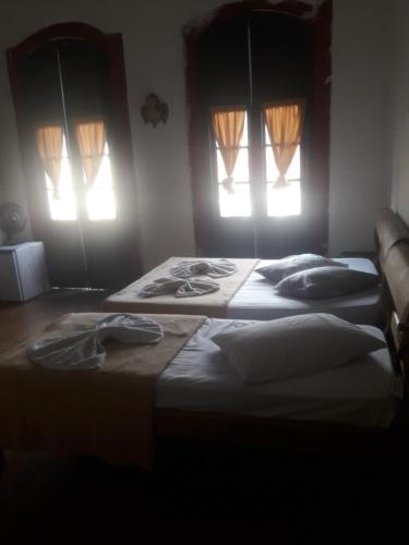 two beds in a room with two windows at Pousada Tiradentes in Ouro Preto