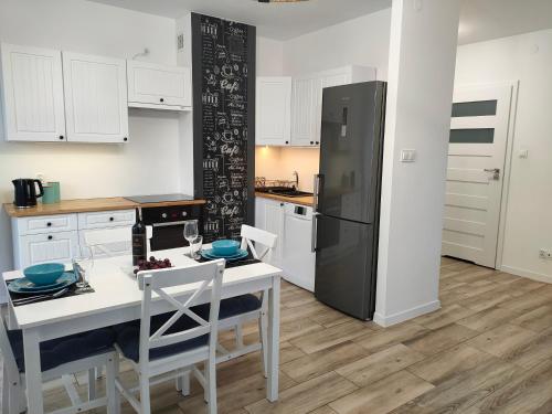 a kitchen with white cabinets and a black refrigerator at Apartamenty Oleńka I - Szczytno Mazury in Szczytno