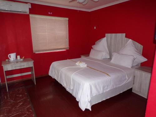 um quarto vermelho com uma cama branca e uma parede vermelha em Khaya B&B na Cidade do Cabo