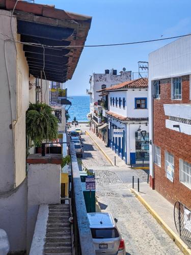 a city street with buildings and the ocean in the background at Chanclas Hostel Vallarta in Puerto Vallarta