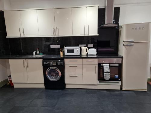 a kitchen with a washing machine and a microwave at County Studio in Ipswich