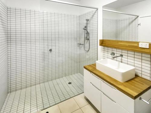 a white bathroom with a sink and a shower at 1 Bright Point Apartment 4502 in Nelly Bay