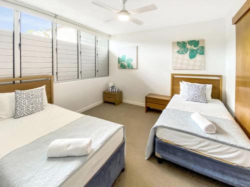 a bedroom with two beds and a window at 1 Bright Point Apartment 4502 in Nelly Bay
