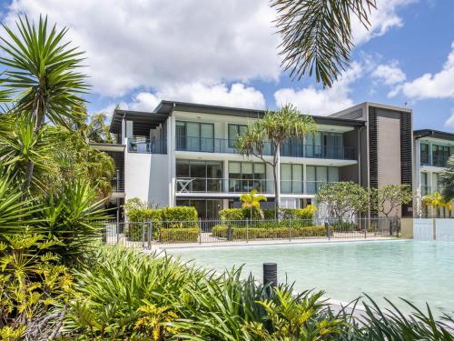 an apartment building with a swimming pool and palm trees at Blue on Blue Apartment 1015 in Nelly Bay