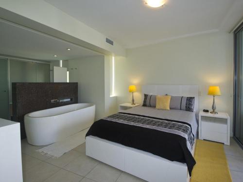 een slaapkamer met een groot bed en een bad bij Blue on Blue Apartment 921 in Nelly Bay