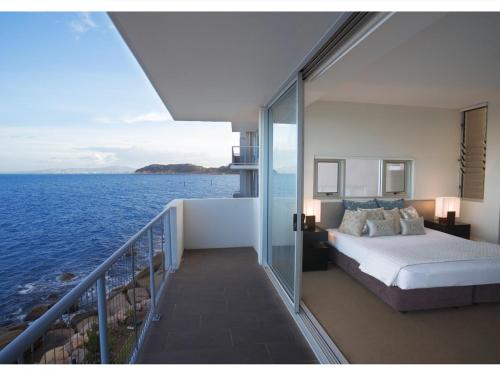 a bedroom with a bed and a balcony with the ocean at 1 Bright Point Apartment 5201 in Nelly Bay