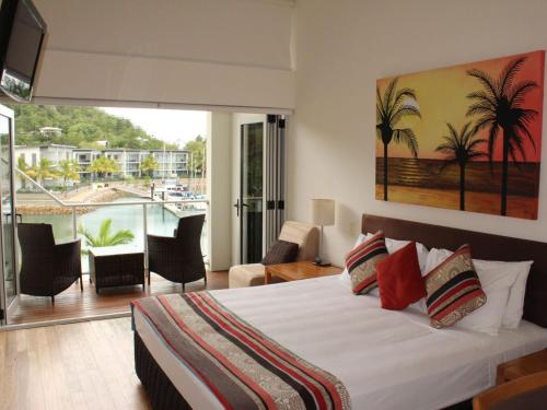 a bedroom with a bed and a balcony with palm trees at Beachside Apartment 17 in Nelly Bay