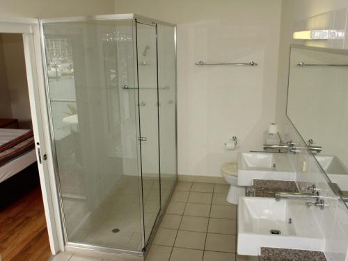 a bathroom with a glass shower and two sinks at Beachside Apartment 17 in Nelly Bay