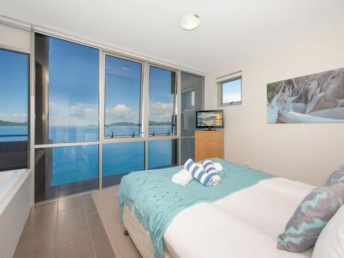 a bedroom with a bed with a view of the ocean at 1 Bright Point Apartment 4501 in Nelly Bay