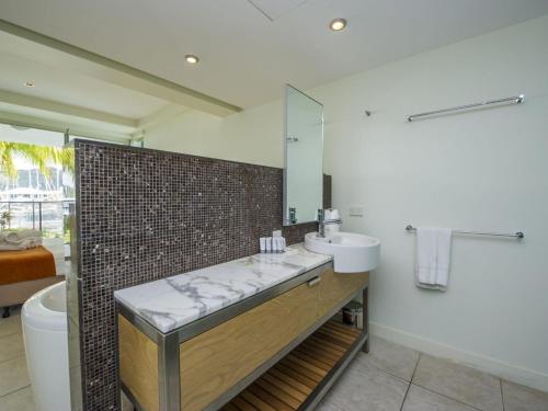 a bathroom with a sink and a tub and a mirror at Blue on Blue Apartment 1011 in Nelly Bay