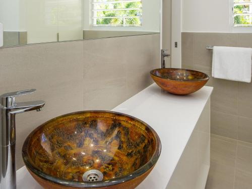Reflections Topaz Villa 2 في Picnic Bay: حمام مع حوض ووعاء على منضدة