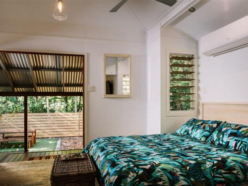 a bedroom with a bed and a sliding glass door at The Little Bush Hut in Nelly Bay