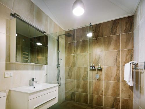 a bathroom with a shower and a sink and a mirror at The Little Bush Hut in Nelly Bay