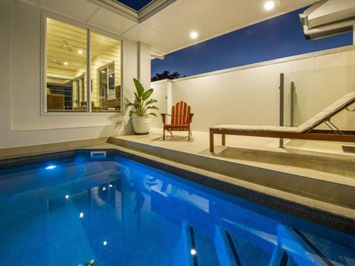 una piscina en una casa con sofá y silla en Reflections Emerald Villa 1, en Picnic Bay