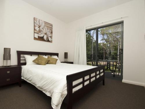 um quarto com uma cama grande e uma janela grande em Woodville Beach Townhouse 6 em Arcadia