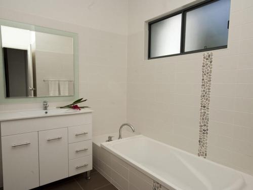 a bathroom with a tub and a sink and a mirror at Woodville Beach Townhouse 6 in Arcadia