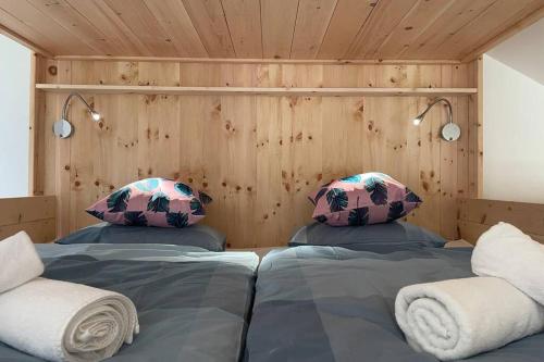 dwa łóżka w pokoju z drewnianymi ścianami w obiekcie Galerie Wohnung Hechelstein / Top 106 w mieście Tauplitz