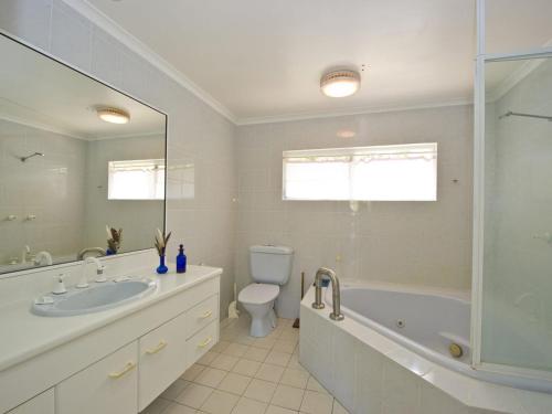 a bathroom with a tub and a toilet and a sink at Johns Tropical Island Home in Nelly Bay