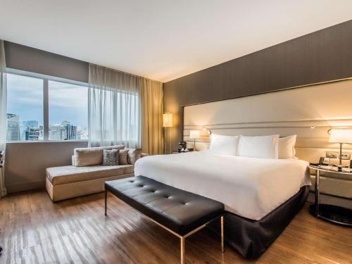 um quarto de hotel com uma cama grande e um sofá em Pullman Sao Paulo Vila Olimpia em São Paulo