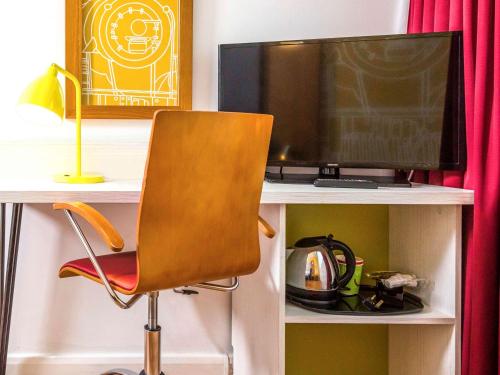 a computer desk with a chair and a television at ibis Styles Crewe in Crewe