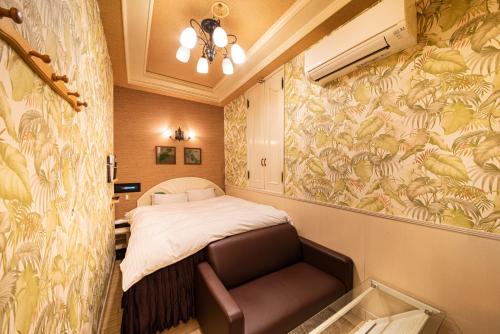 a bedroom with a bed and a chair in it at リトル チャペル ココナッツ 天王寺 in Osaka