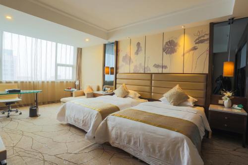 淮安にあるHuai'an Jinling Hotelのベッド2台とデスクが備わるホテルルームです。