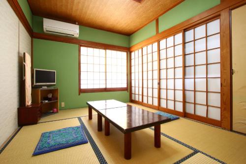 a living room with a table in a room with windows at kangetsusou in Unzen