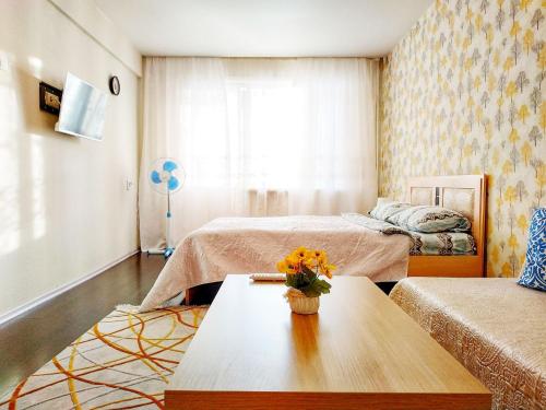 アンガルスクにある1-к квартира Rise & Shine 32 Mikrorayonのベッド2台、テーブル(花付)が備わる客室です。
