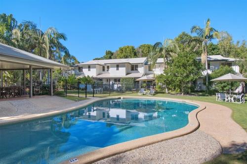 a swimming pool in front of a house at Byron Lakeside Holiday Apartments in Byron Bay