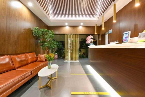a lobby with a brown leather couch and a table at Xingshe Alley Courtyard Hotel Beijing Wangfujing Forbidden City Branch in Beijing
