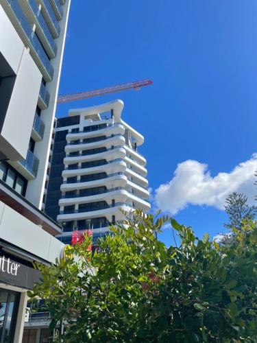 a tall white building with a crane in the sky at X Kirra Apartments in Gold Coast