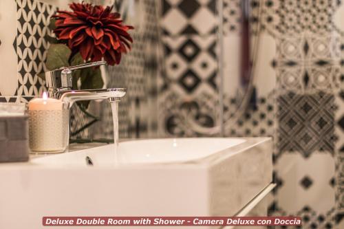 a bathroom sink with a vase with a red flower at 4 Star Bologna Train Station - Self Check-In in Bologna