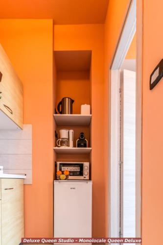 a kitchen with orange walls and a small refrigerator at 4 Star Bologna Train Station - Self Check-In in Bologna