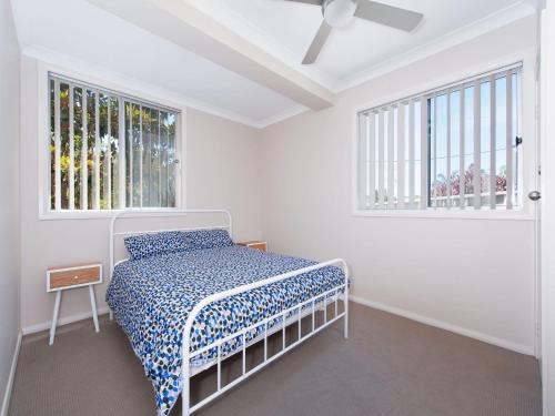 ein weißes Schlafzimmer mit einem Bett und einem Fenster in der Unterkunft Magnolias in Fingal Bay