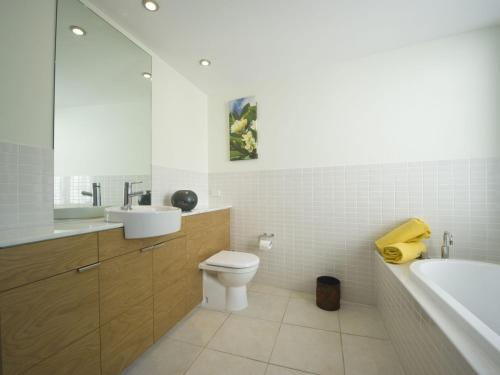 een badkamer met een toilet, een wastafel en een bad bij Blue on Blue Apartment 921 in Nelly Bay