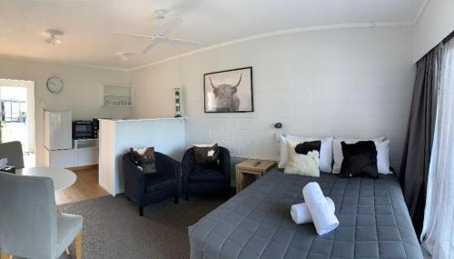 a living room with a bed and two chairs at Racecourse Motel in Paeroa