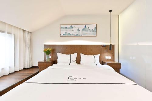 a bedroom with a large bed with white sheets at Xingshe Alley Courtyard Hotel Beijing Wangfujing Forbidden City Branch - Breakfast included & English speaking reception & Free WiFi and Laundry room & Hutong Culture & Cat-keeping & Flower-growing Terrace & One day tour service & Free coffee in Beijing