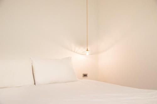 a white bed with a white pillow in a room at OwlStay Jiufen Green Ray - 故事所 山中夢遊 九份綠光 in Jiufen