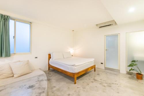 a white room with a bed and a couch at OwlStay Jiufen Green Ray - 故事所 山中夢遊 九份綠光 in Jiufen