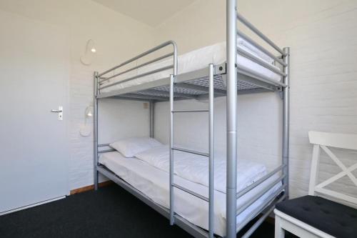 Holiday home het Zeepaardje في نوردويكرهوت: غرفة نوم بسريرين بطابقين مع ملاءات بيضاء