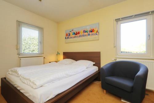 a bedroom with a bed and a black chair at Holiday home Zeelust in Noordwijkerhout