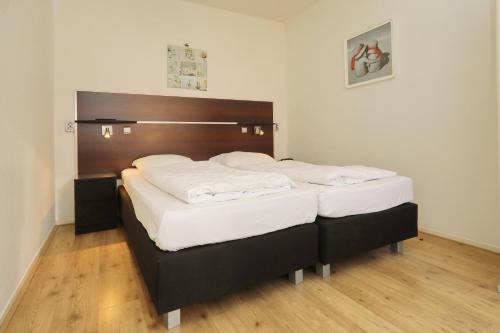 um quarto com 2 camas e lençóis brancos em Holiday home de Zeester em Noordwijkerhout