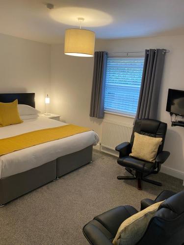 a bedroom with a bed and a chair and a window at Tirah Guest House in Aldeburgh