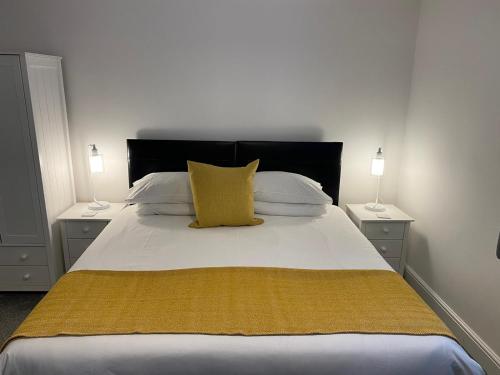a bedroom with a large bed with a yellow pillow at Tirah Guest House in Aldeburgh