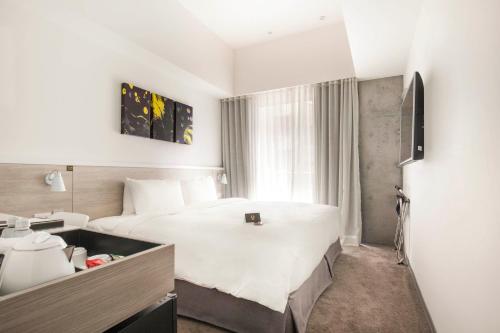 a hotel room with a large white bed and a window at CityInn Hotel Plus- Fuxing North Road Branch in Taipei