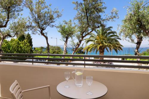 a table with two glasses on a balcony with trees at Akti Taygetos - Conference Resort in Kalamata