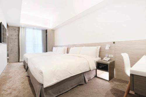 a bedroom with a large white bed and a telephone at CityInn Hotel Plus- Fuxing North Road Branch in Taipei