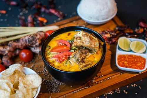 a bowl of soup on a wooden table with food at Swiss-Belhotel Serpong in Serpong