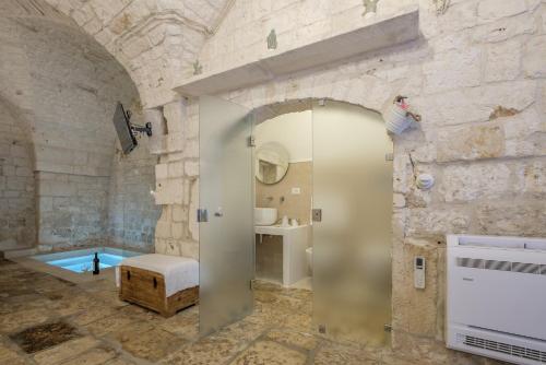 a bathroom with a shower and a tub in a stone wall at Dama Bianca Boutique Hotel Ostuni in Ostuni